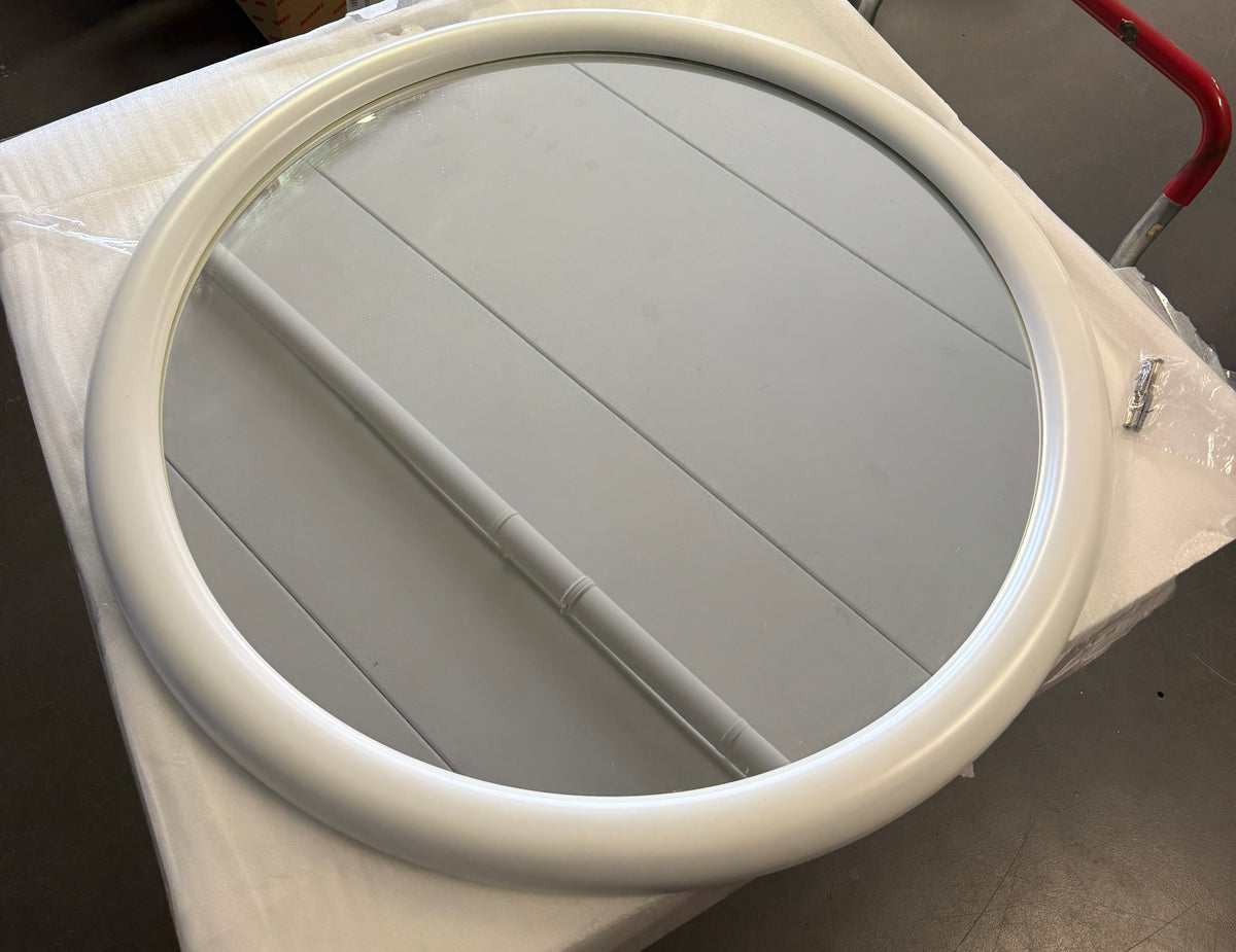 Rund spegel med vit ram sedd uppifrån, förpackad på lastpall