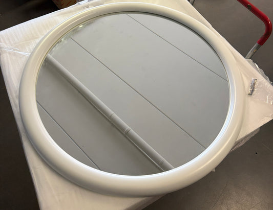 Rund spegel med vit ram sedd uppifrån, förpackad på lastpall