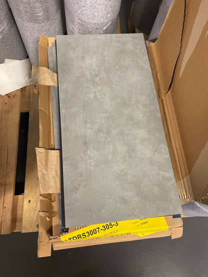 Vinylklinkerplatta 305x609 mm i ljusgrå betongmönster ovanpå öppnad förpackning