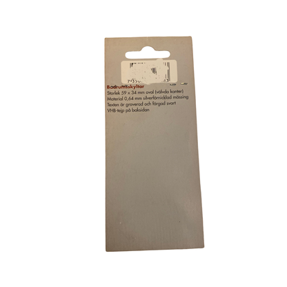 Baksida av förpackning för oval badrumsskylt WC med mått 59 x 34 mm, material och VHB-tejp